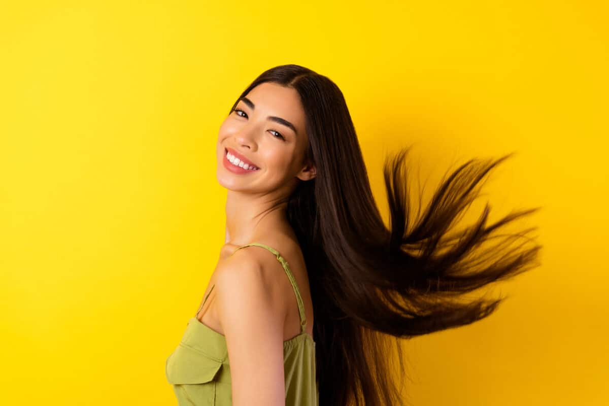 Profile portrait of cheerful adorable person beaming smile flying black hair isolated on yellow color background