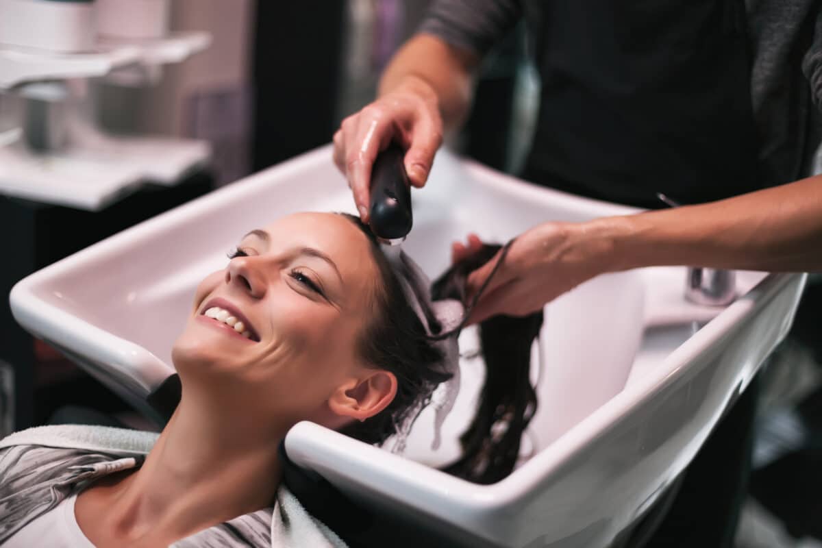 Woman at the washing bowl gettin a Dry or Oily Scalp Detox Treatment