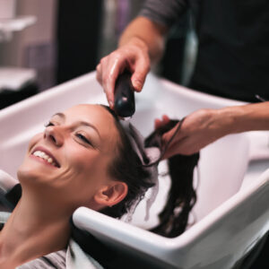 Woman at the washing bowl gettin a Dry or Oily Scalp Detox Treatment